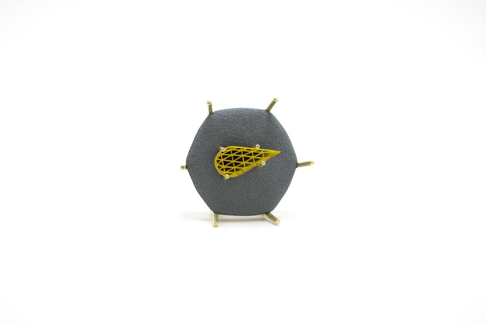 Hexagonal charcoal brooch with a gold mesh leaf, held by gold prongs