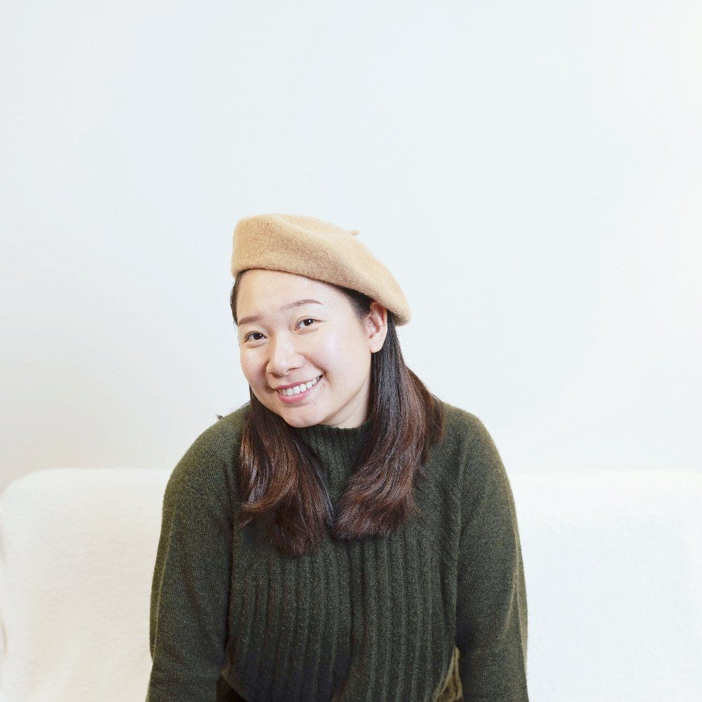 Portrait of Danni Xu smiling, in a camel beret and olive-green knit sweater