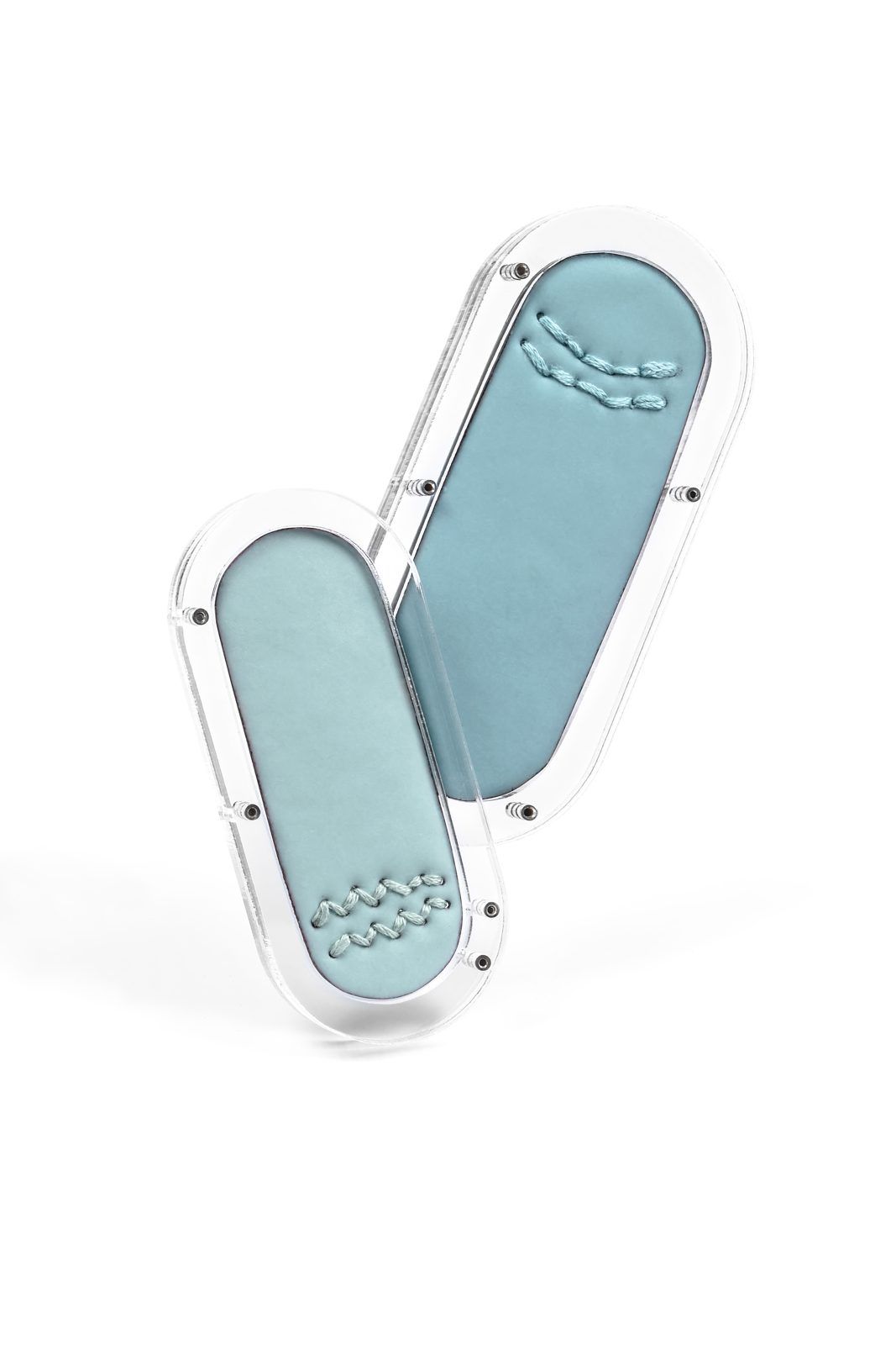 Pair of pill-shaped blue enamel brooches in clear acrylic