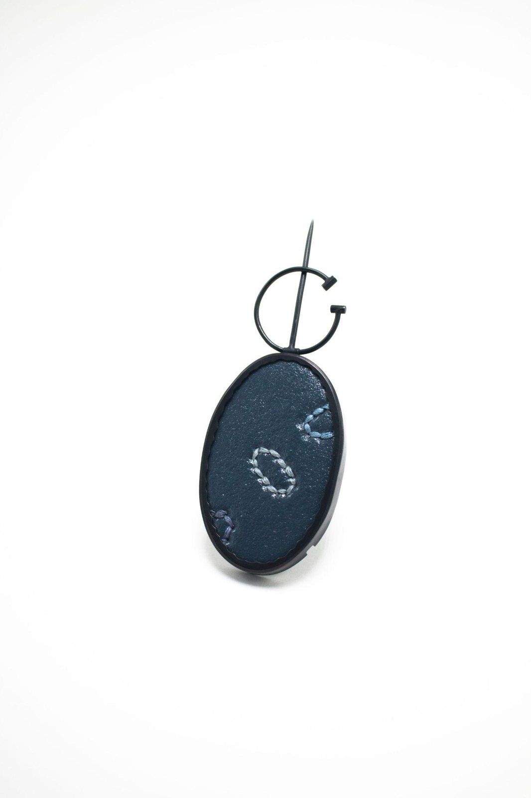 Oval dark blue enamel brooch with embroidered stitching