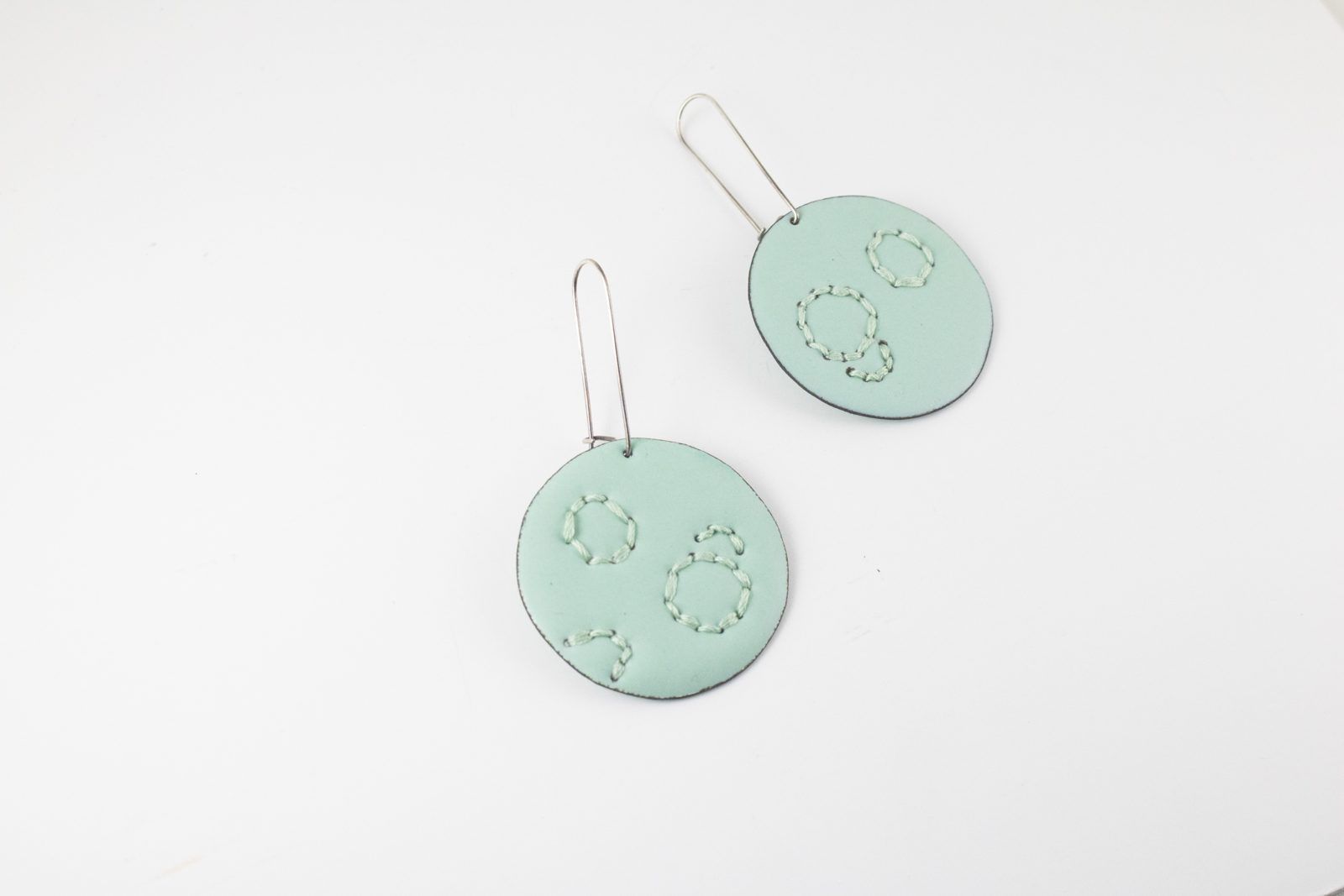 Oval sage-green enamel drop earrings with stitched dots