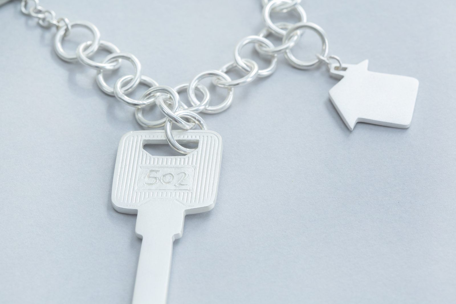 Silver key and house charms on a chain bracelet