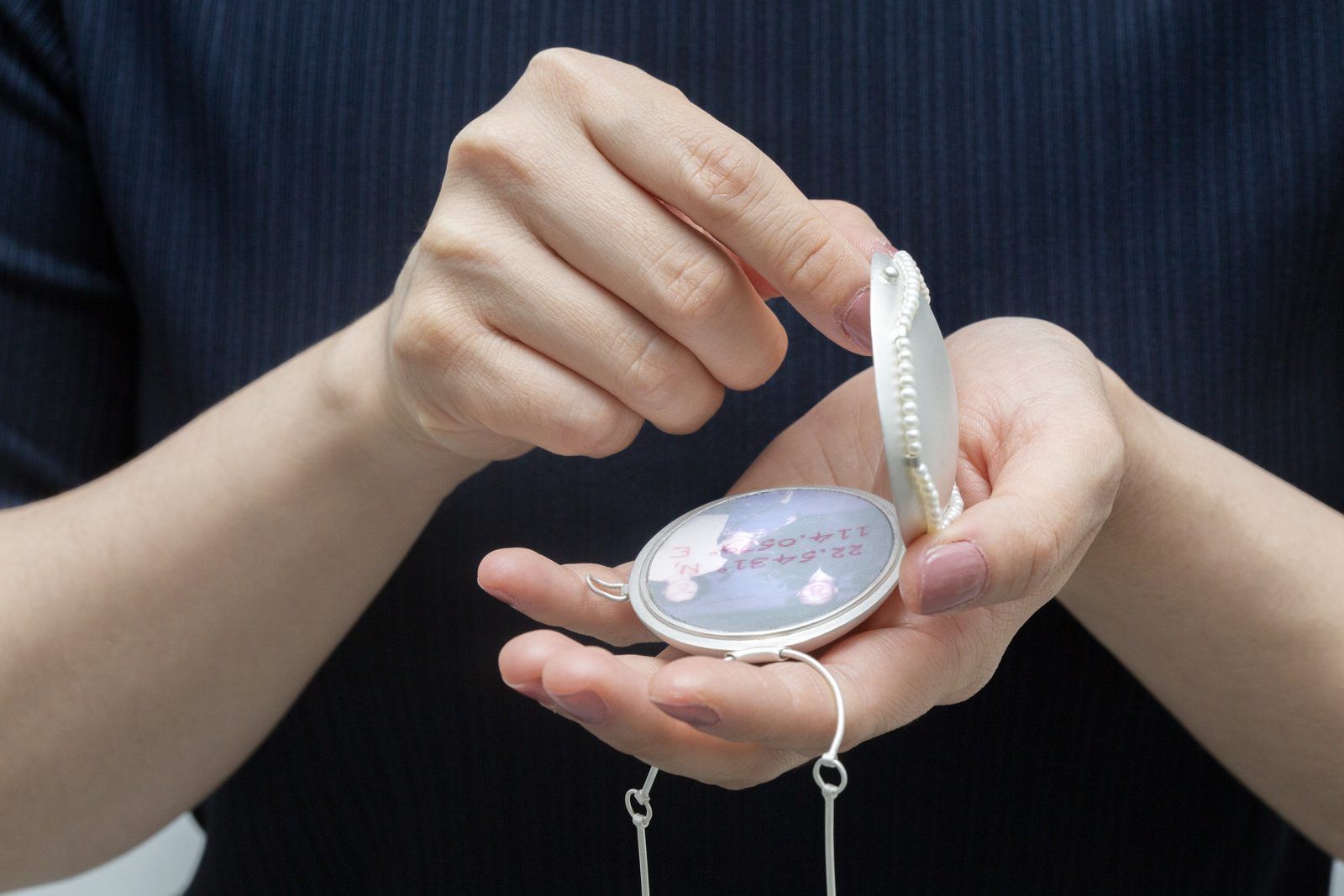 Hands opening a silver locket holding a family photograph