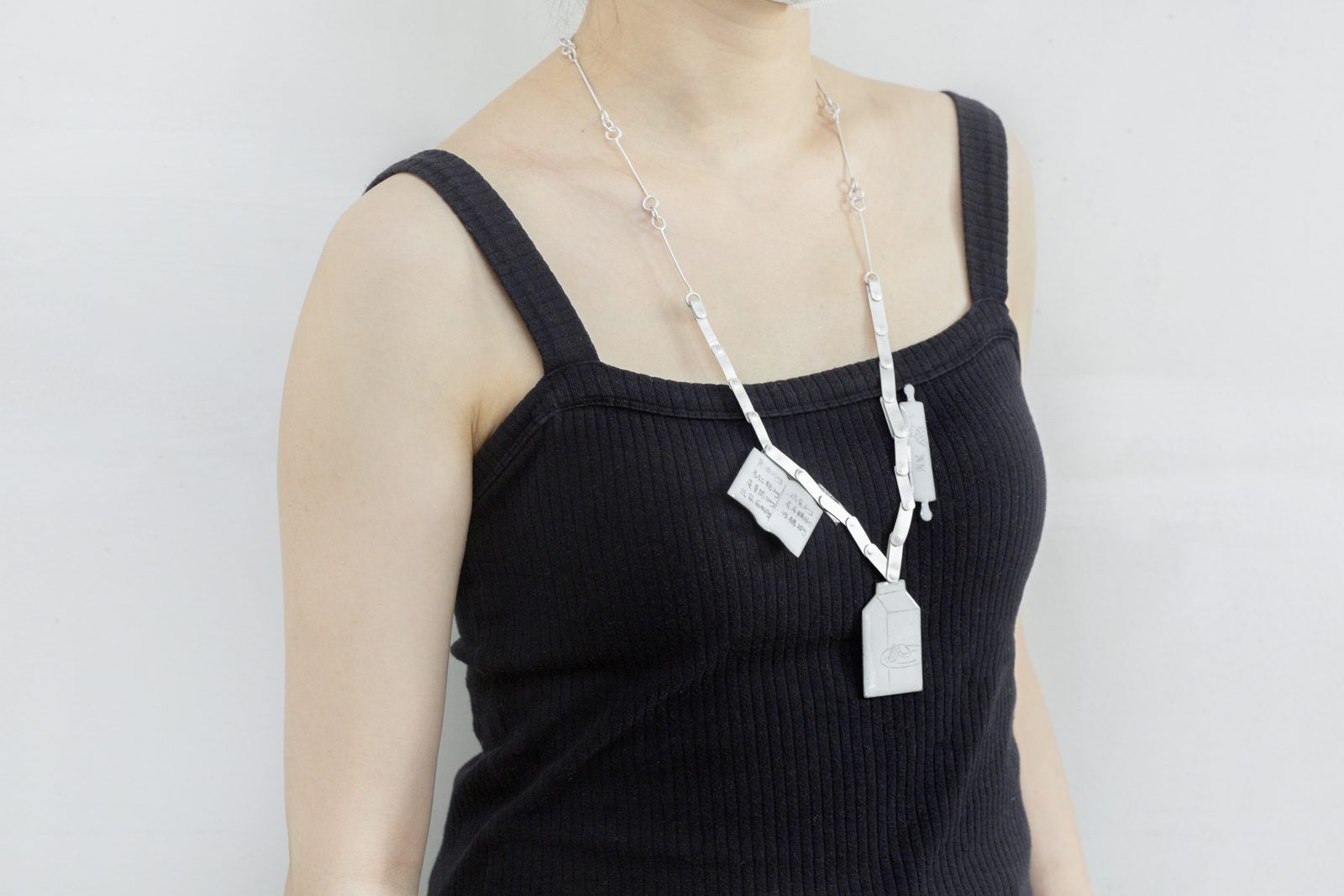 A woman wearing a necklace of white enamel tags