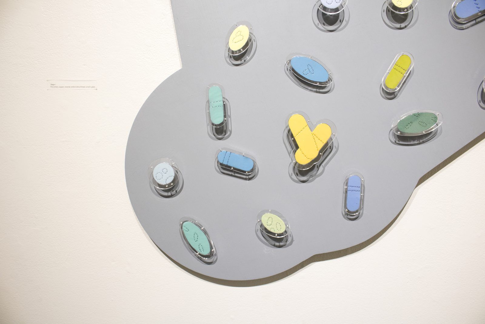 Gray cloud-shaped panel set with small colored enamel pills